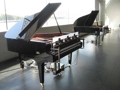 Zwei Klaviere stehen hintereinander in einem Raum. 