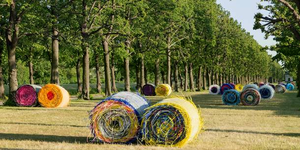 Ansicht der Kunstinstallation "Ballenernte" von Michael Beutler im Großen Garten Herrenhausen: farbige Stroh(halm)ballen 